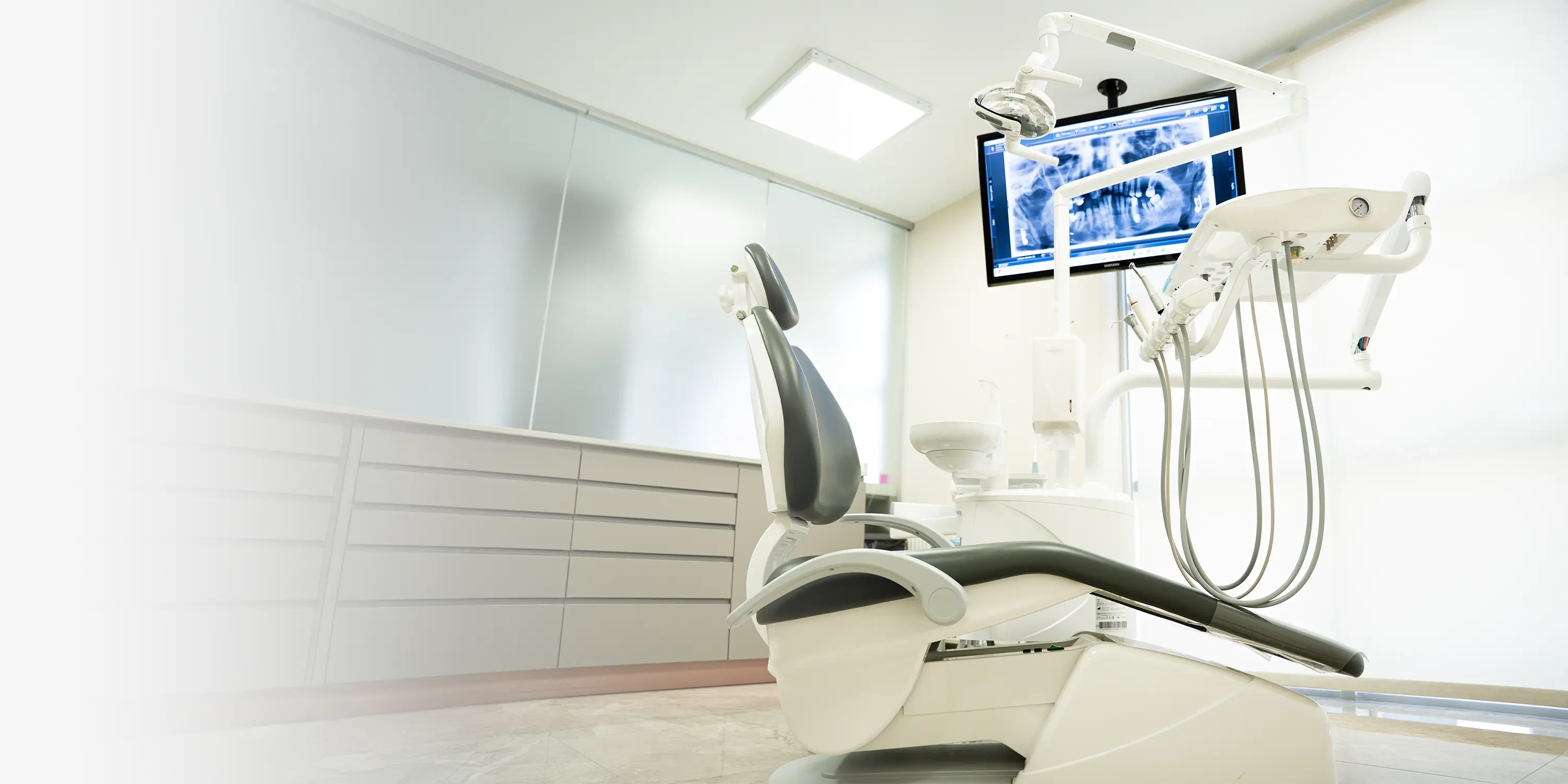 DentVisit treatment room — dental chair, overhead light and a chairside screen showing a panoramic dental X-ray